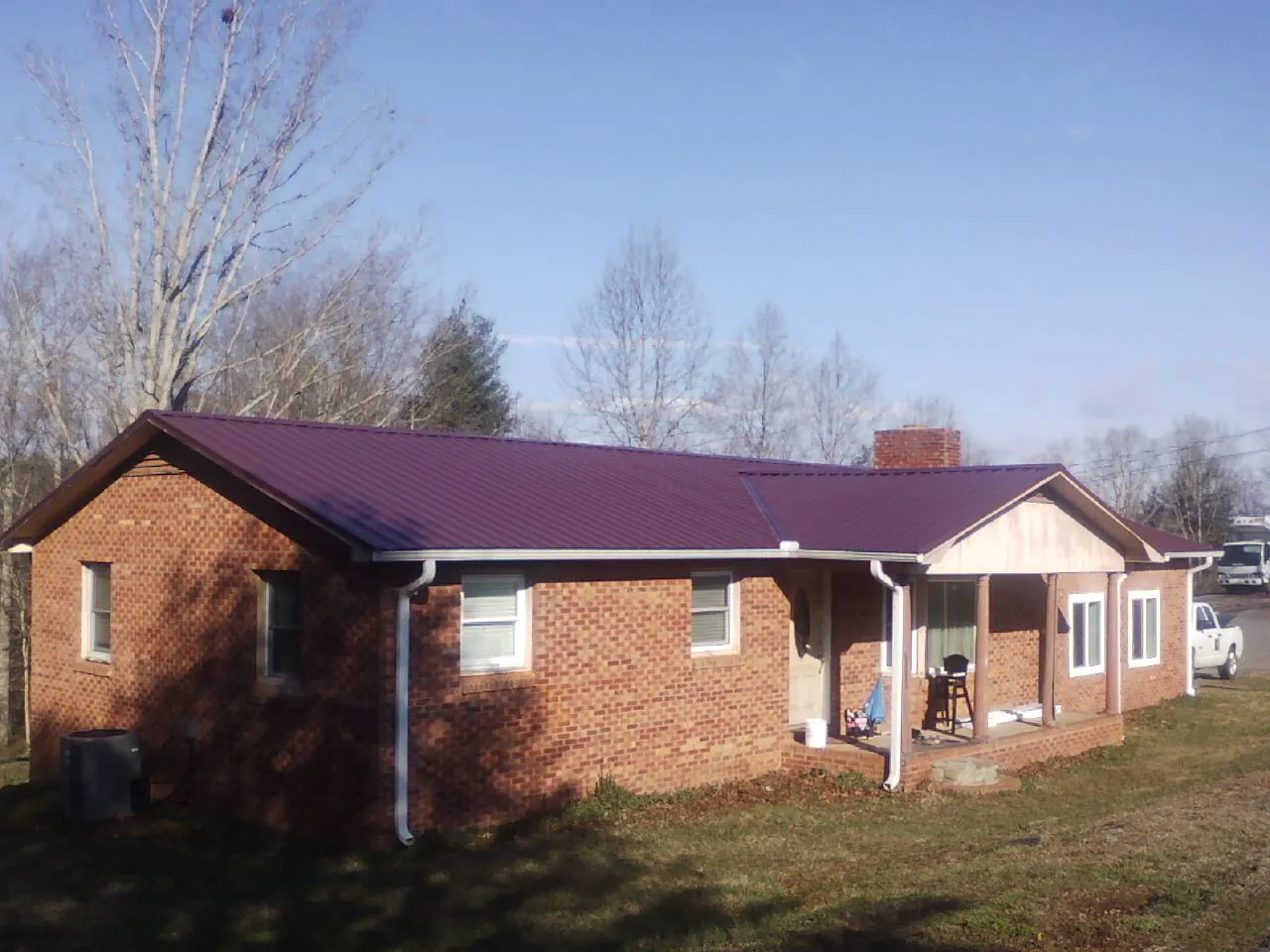 Burgundy metal roof on a brick ranch home with a new addition in Cromwell